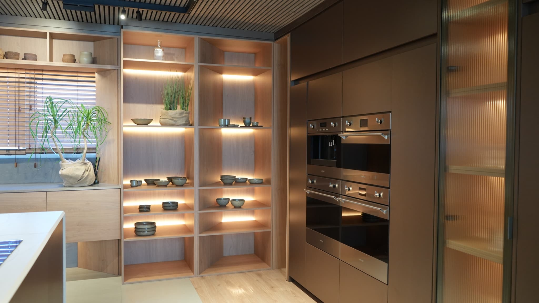 Estantería iluminada y hornos empotrados en la cocina